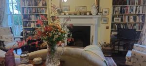 a living room with a fireplace and a vase of flowers at Dromore House Historic Country house in Coleraine