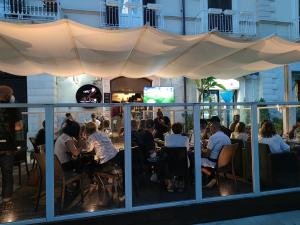 a group of people sitting at tables in a restaurant at Maison Divino in Trani