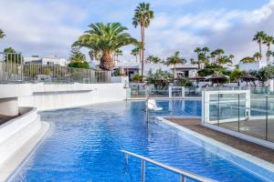 a swimming pool at a resort with palm trees at Jardines del Sol in Playa Blanca