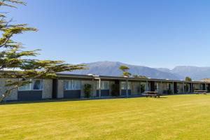 a house with a large yard with mountains in the background at Heartland Hotel Haast in Haast