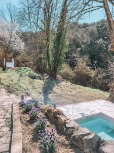a garden with a swimming pool and purple flowers at Casa Om in Dosríus