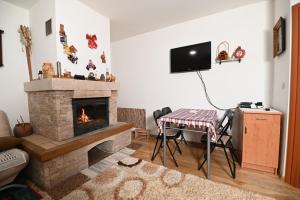 a living room with a fireplace and a table and a tv at Apartment Tom in Jahorina