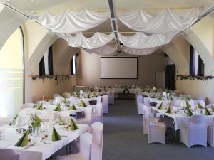 un salón de banquetes con mesas y sillas blancas en JUFA Hotel Seckau en Seckau