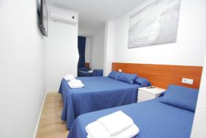 a room with two beds with blue sheets at Hotel Tres Leones in Vilassar de Mar