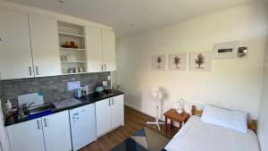 a kitchen with white cabinets and a bed in a room at Studio Flatlet on Montreal in Cape Town