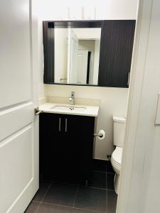 La salle de bains est pourvue d'un lavabo, d'un miroir et de toilettes. dans l'établissement Fully Equipped 1BR Condo Vaughan - Toronto, à Vaughan