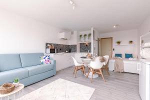 ein Wohnzimmer mit einem blauen Sofa und einer Küche in der Unterkunft Moderne lichtrijke studio vlakbij strand en casino Middelkerke in Middelkerke