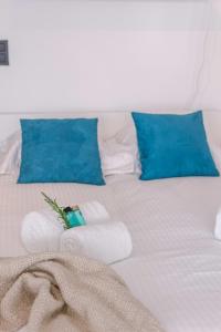 ein weißes Bett mit blauen Kissen und Handtüchern darauf in der Unterkunft Moderne lichtrijke studio vlakbij strand en casino Middelkerke in Middelkerke