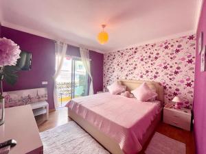 1 dormitorio con paredes moradas y 1 cama con sábanas rosas en Belle suite / belles vacances, en Olhão