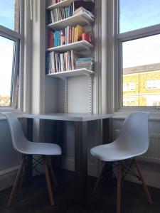 a table and two chairs in front of a book shelf at Studio Flat in London