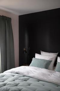 een slaapkamer met een wit bed en een zwarte muur bij La Maison Plûme in Villequier