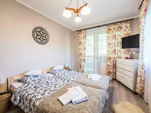 a bedroom with a bed and a dresser and a window at Apartament BrzyZek in Zakopane