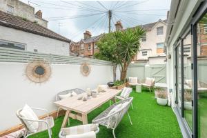 un patio con una mesa y sillas en un césped verde en The Shell House (Sleeps 12 - 5 mins to Beach), en Bournemouth