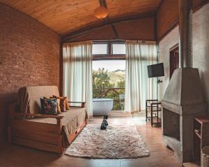 uma sala de estar com um sofá, uma banheira e uma janela em Chalé Gaia com Banheira relaxante em São Bento do Sapucaí
