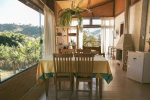 d'une salle à manger avec une table, des chaises et une fenêtre. dans l'établissement Chalé Gaia com Banheira relaxante, à São Bento do Sapucaí