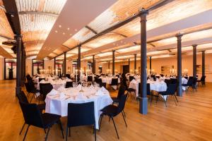 a banquet hall with white tables and black chairs at Riverside in Zweidlen