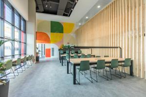 une cafétéria avec des tables et des chaises et un mur coloré dans l'établissement Micampus Wynwood - Xaudaro, à Madrid