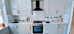 a kitchen with white cabinets and a stove top oven at Central Reading Modern 3BR flat - Walk to station and high street in Reading +6 photos