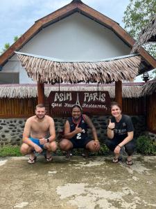 a group of men sitting in front of a sign at Asim Paris Guesthouse in Bukit Lawang