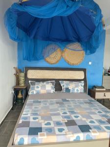 1 dormitorio con 1 cama con pared azul en la maison du nord en Acoua