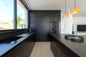 a kitchen with black cabinets and a large window at Villa Andrea, quiet luxury, sunset with sea views in Adeje