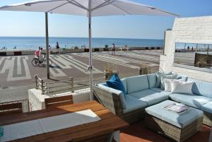 a patio with a couch and an umbrella and the beach at Strandzicht Zandvoort in Zandvoort