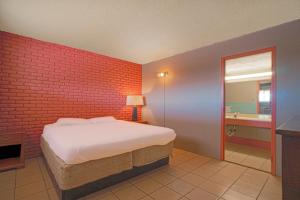 a bedroom with a bed and a brick wall at Town & Country Motel Bossier City by OYO in Bossier City