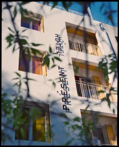 un edificio blanco con escritura a un lado. en Hôtel Présent en Arles
