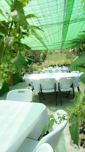 a group of white tables and chairs in a garden at Camping D'Tente Paradise in Saint-Louis