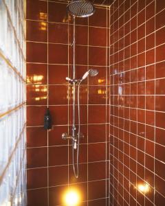 y baño con ducha y azulejos marrones. en Hôtel Présent en Arles