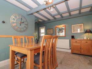 a dining room with a table and chairs and a clock at Stillwater Cottage in Beverley