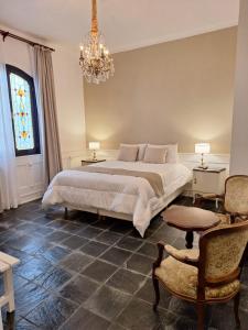 a bedroom with a large bed and a chandelier at Posada del Cerro in Salta +7 photos