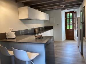 a kitchen with white cabinets and a white chair at La Casina de Inesita in Cadavedo