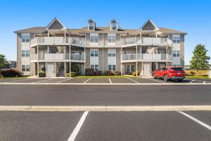 a large apartment building with a red car parked in a parking lot at Bethany Bay -- 37185 Harbor #3602 in Ocean View