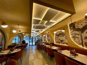 a dining room with tables and chairs and paintings on the walls at Hotel Le Grandeur in Bangalore