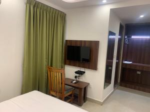a bedroom with a bed and a desk and a television at Hotel Le Grandeur in Bangalore