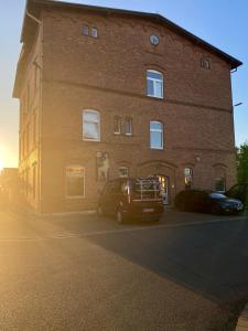 a large brick building with cars parked in front of it at Zollzeche Stadtwohnungen in Staßfurt