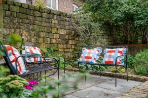 two benches with pillows sitting in a garden at 17 Trinity Lane in York
