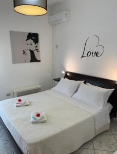 ein Schlafzimmer mit einem großen weißen Bett mit zwei Rosen darauf in der Unterkunft THE AIRPORT HOUSE in Catania