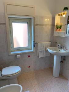 ein Bad mit einem WC, einem Waschbecken und einem Fenster in der Unterkunft THE AIRPORT HOUSE in Catania