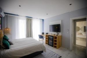 a bedroom with a bed and a desk and a television at Cowork Lab Suites in Maputo
