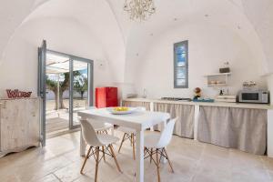 a white kitchen with a white table and chairs at Lamia Madreperla by BarbarHouse in San Vito dei Normanni