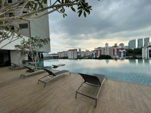 a swimming pool with chairs and a city skyline at Mid Valley Luxury 6pax Resort谷中城奢华风格套房 in Kuala Lumpur