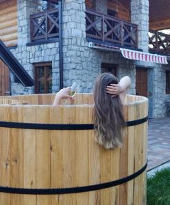 uma mulher a olhar para o telemóvel numa banheira de madeira em Vucje Brdo in Kolasin em Kolašin