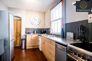 uma cozinha com um frigorífico e um relógio na parede em Spacious Entire Home with Parking by AV Hughes Properties Short Lets & Serviced Accommodation Northampton - For Business & Families em Northampton