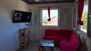sala de estar con sofá rojo y 2 ventanas en Bungalow de 2 chambres avec vue sur la mer jardin clos et wifi a Anse Bertrand, en Anse-Bertrand