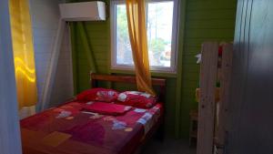 Habitación pequeña con cama y ventana en Bungalow de 2 chambres avec vue sur la mer jardin clos et wifi a Anse Bertrand, en Anse-Bertrand
