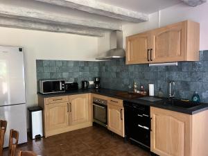 a kitchen with wooden cabinets and a black counter top at Maison de Preuillé in Payré