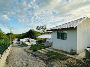 uma pequena casa branca com um quintal e uma piscina em Chacara em Ubatiba-Maricá em Maricá