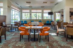 um restaurante com mesas e cadeiras e uma televisão de ecrã plano em Hilton Garden Inn Orlando East - UCF Area em Orlando